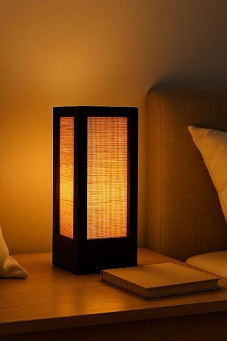 Warm glowing table lamp on bedside table beside a book