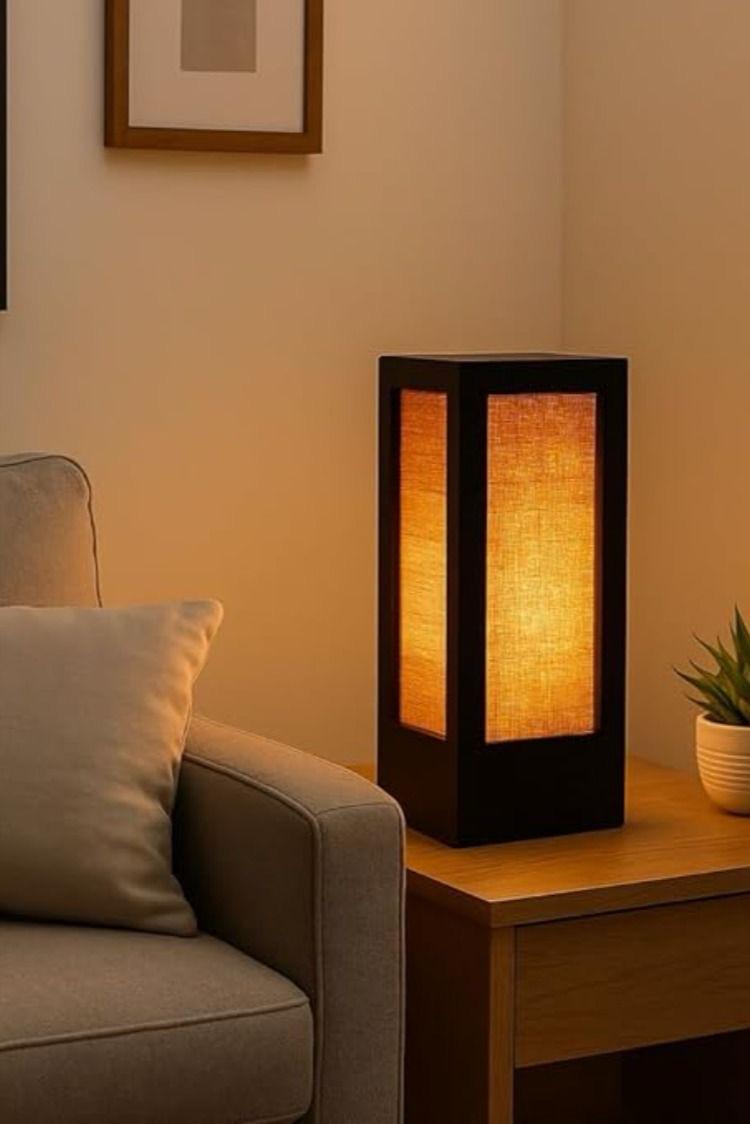 Dark framed table lamp on side table beside a sofa